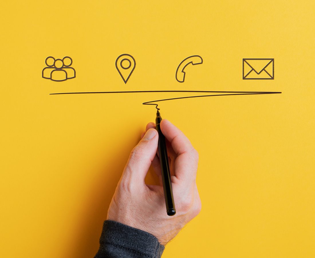 Male hand underlining hand drawn contact and communication icons on yellow background. With copy space.